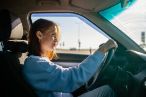 A young female driver behind the wheel with a provisional license.