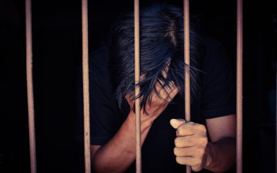 Man holding head behind prison bars