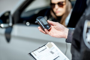 Police officer holding BAC test device. Is it Worth Getting a DUI Lawyer in California?