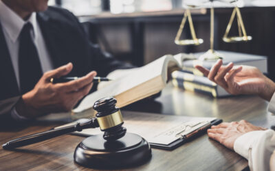 Lawyer sits at desk with client and explains the difference between being acquitted and found not guilty.