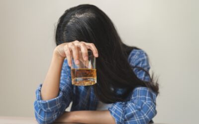 A young woman with long black hair covers her face while holding an alcoholic drink and wondering: Can a DUI prevent you from being a legal guardian or conservator?