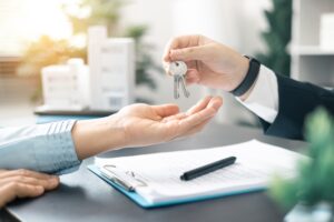 A real estate agent handing the keys to a client. Can you be a real estate agent with a DUI?